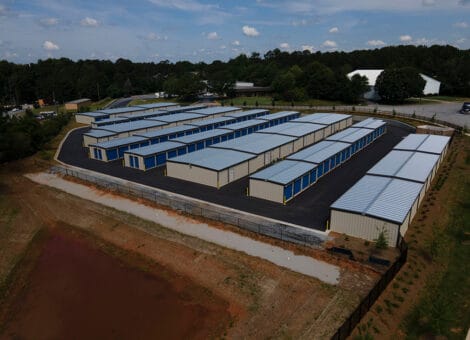 Aerial view of multiple 80×100 mini storage steel buildings with blue roofs and beige walls, showcasing efficient layout and accessibility for storage solutions.
